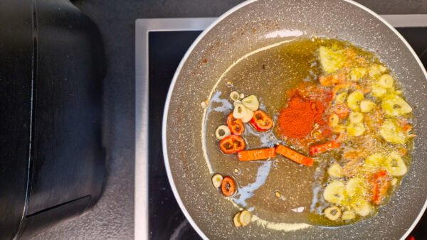 Paprika røres ud i olien med hvidløg og chili
