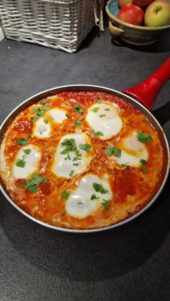 Shakshouka med æg i tomatsauce og urter på toppen