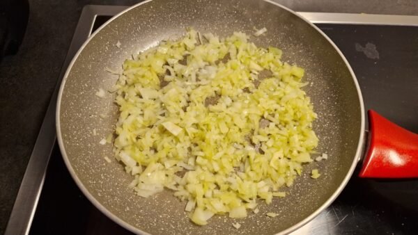 Hakket løg sauteres i olivenolie på en pande